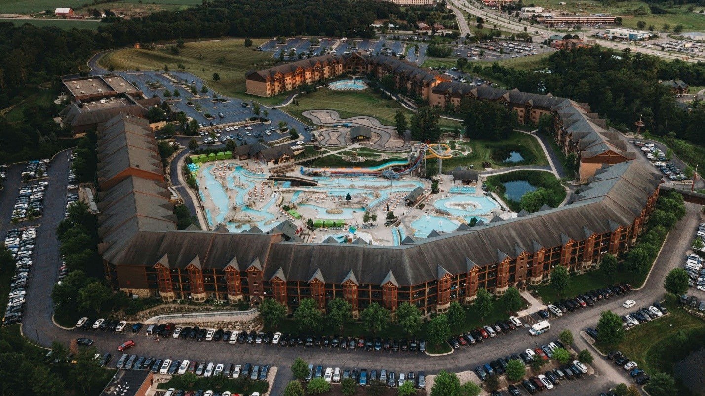 Aerial view of Wilderness Resort’s horseshoe-shaped timber lodge surrounding outdoor waterpark with pools and slides in Wisconsin Dells.