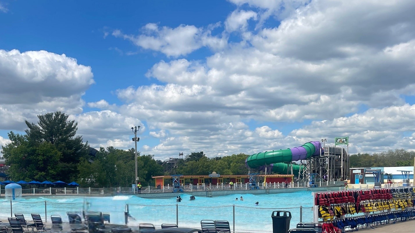 Outdoor pool with lounge chairs, colorful water slides, and dramatic cloudy blue sky at Noah’s Ark Waterpark.